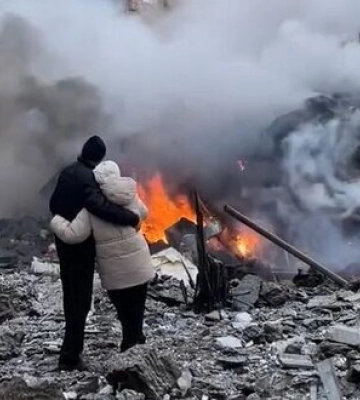 Чоловік та жінка, обійнявшись, дивляться як догорає їх будинок після прильоту російської ракети у Харкові. ВIДЕО