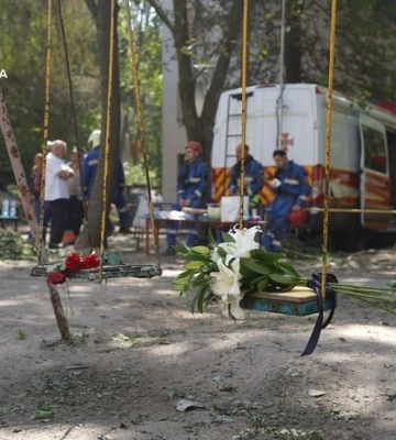 Кияни несуть квіти до знищеного росіянами будинку, де тривають пошукові роботи 